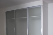 armário em mdf branco com portas de correr com vidros.